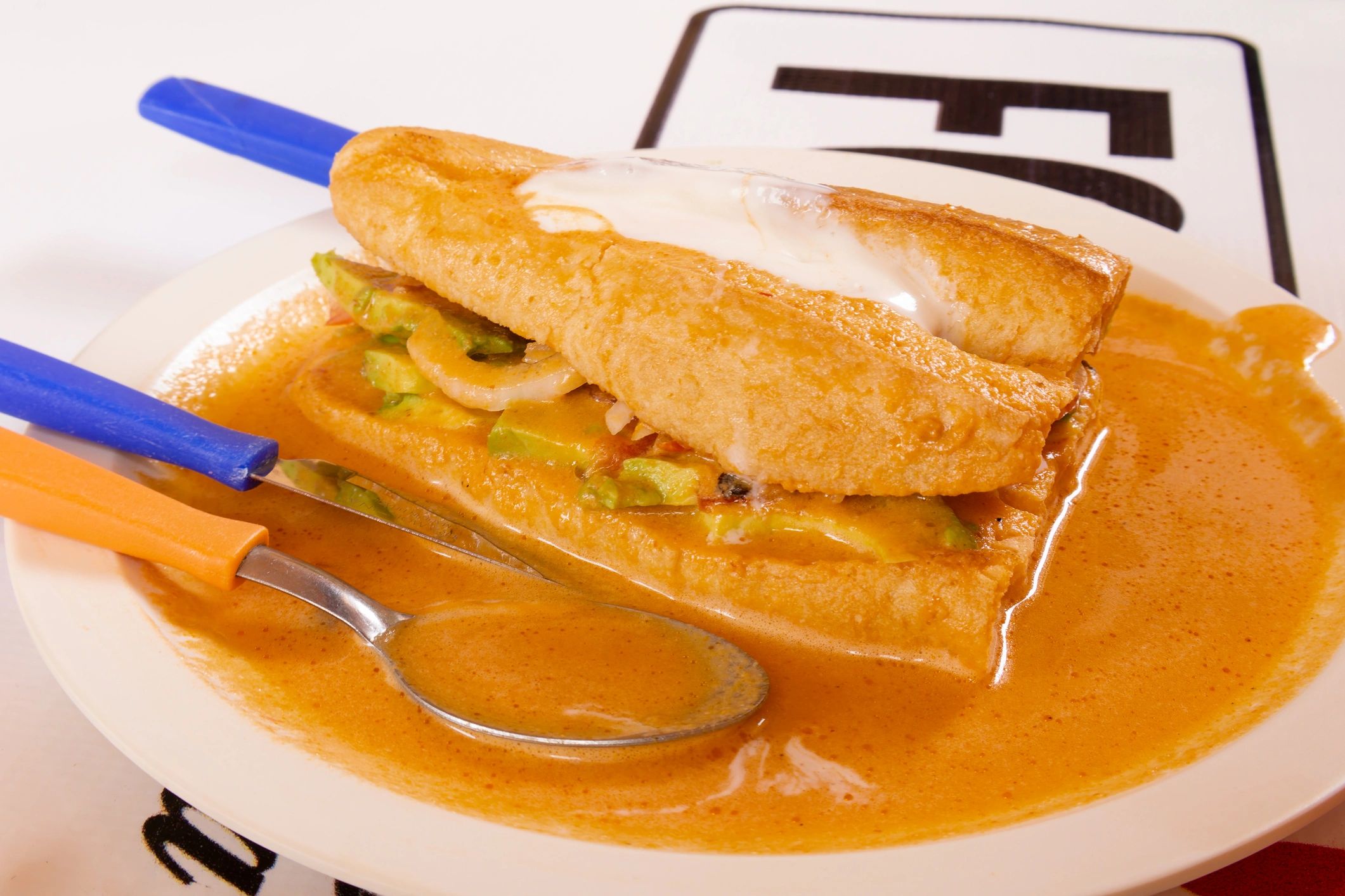 Mexican torta sandwich served with sauce and toppings